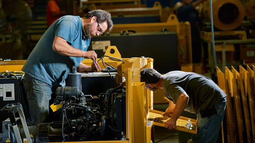 Two employees working on a light tower